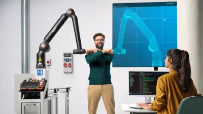 Two associates are playing on a football table with a Bosch Rexroth APAS assistance robot.
